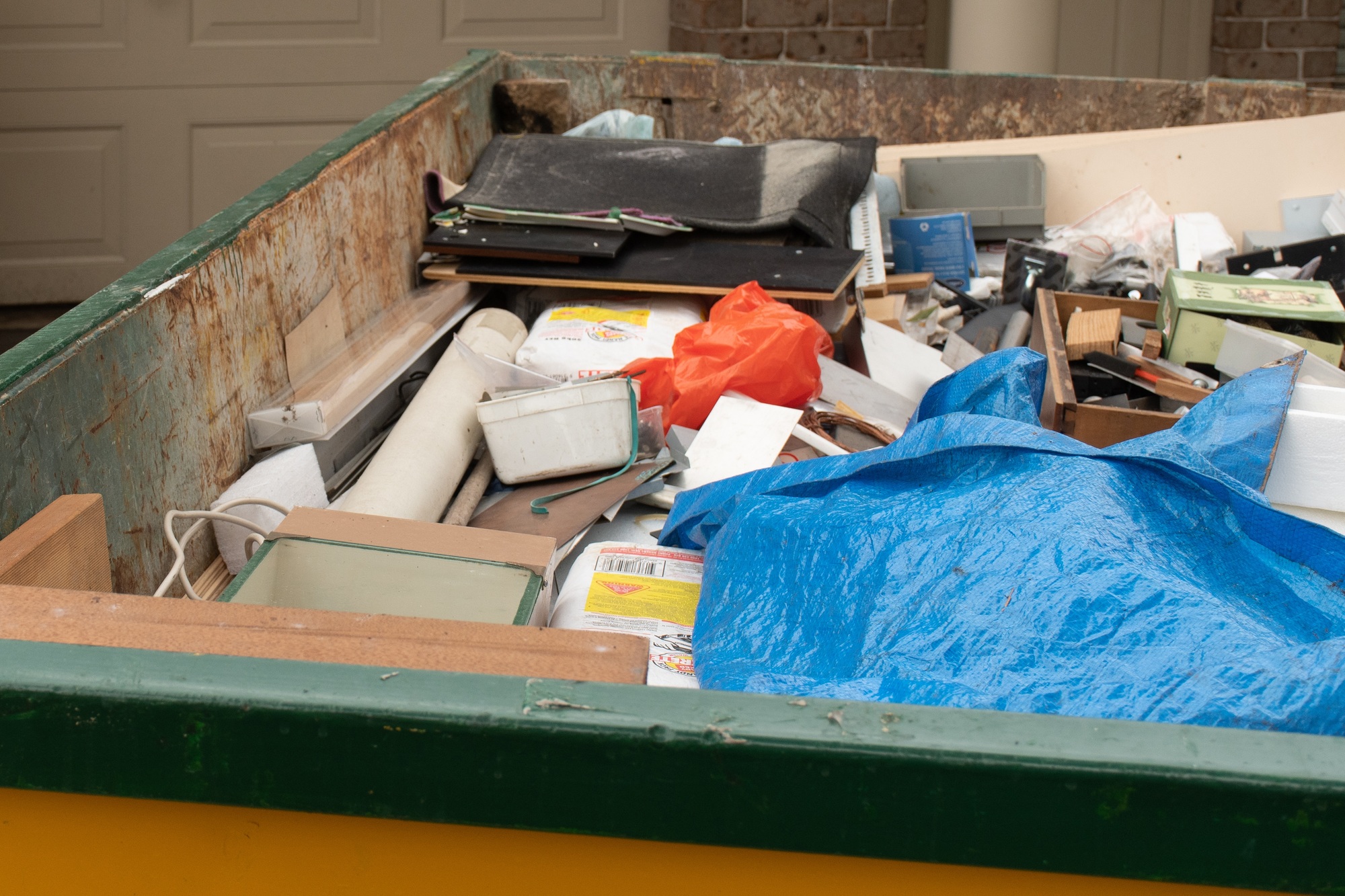 Skip bin full of household waste rubbish on the front yard. House clean up